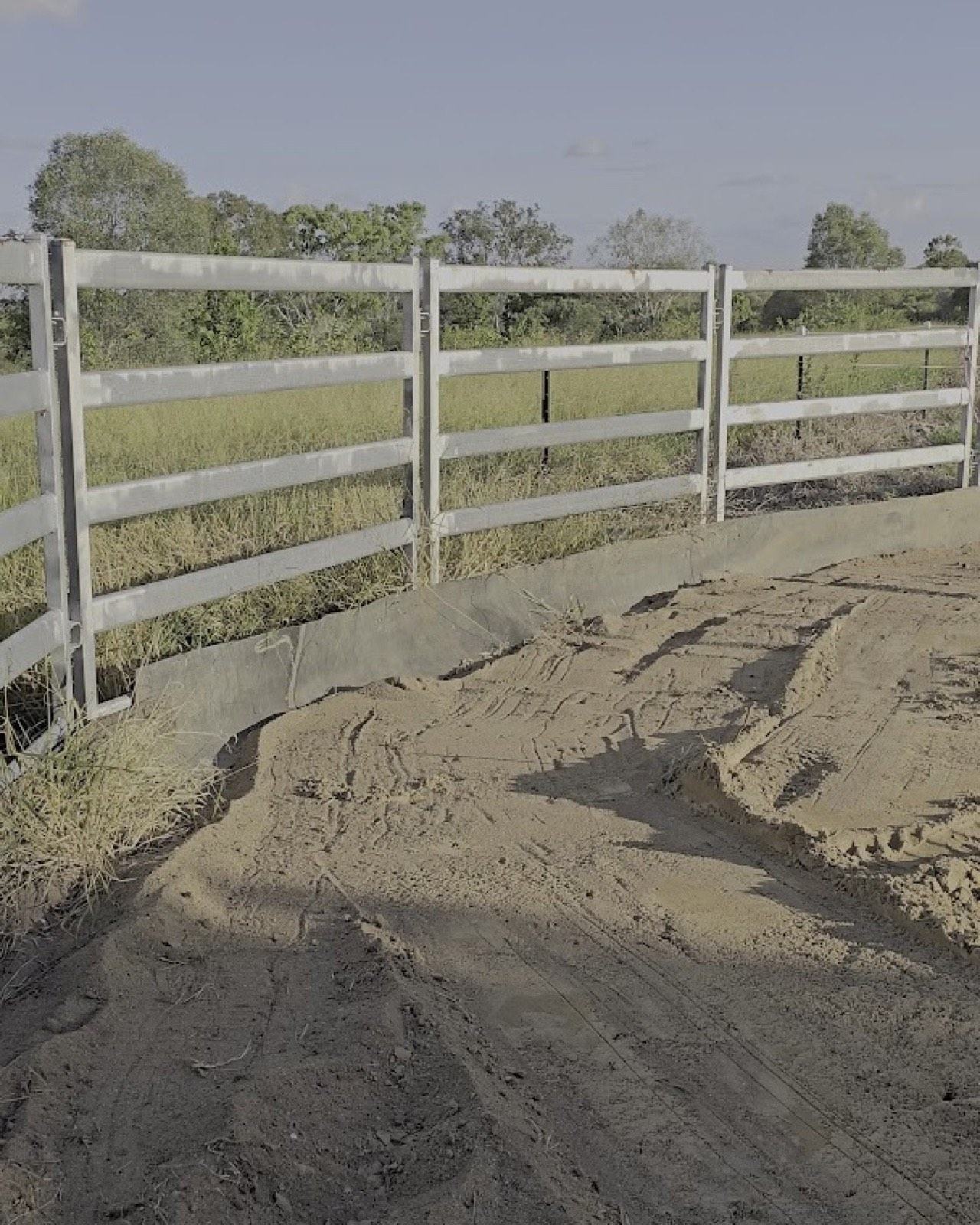 Sand spread and graded into a level pad beside a rural post-and-rail fence